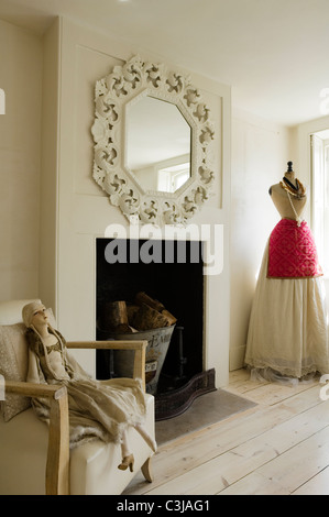 Ornate mirror above fireplace in living room with dressmaker's dummy and mannequin doll on armchair Stock Photo