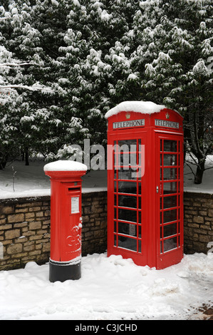 Red mailbox and phone box in the snow England Uk Stock Photo