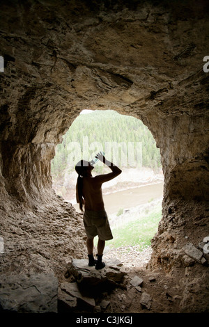 Smith River, Young man drinking water in cave Stock Photo