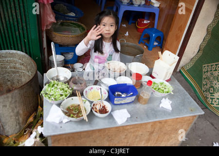 Young Girl selling Dishes, Hanoi, Vietnam Stock Photo