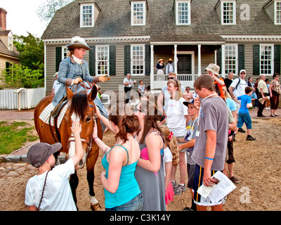 Wearing historic costume, a woman equestrian riding side saddle talks with tourists in Colonial Williamsburg, VA. Stock Photo