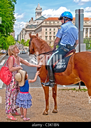 A mother and daughter talk to a U.S. Park Policeman while petting his horse on the National Mall in Washington, D.C. Stock Photo