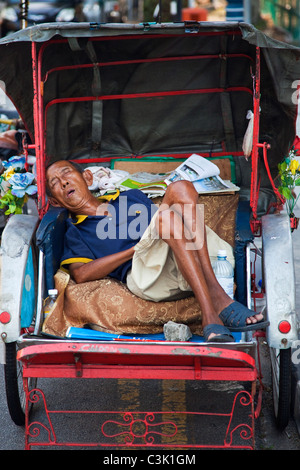 A Man Sleeping in his Rickshaw, Penang Stock Photo