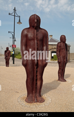 Three figures in the 'Assembly' art installation by Peter Burke beside the River Thames at The Woolwich Armoury, London, UK. Stock Photo