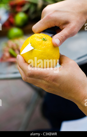 Close up of womans hands peeling lemon Stock Photo