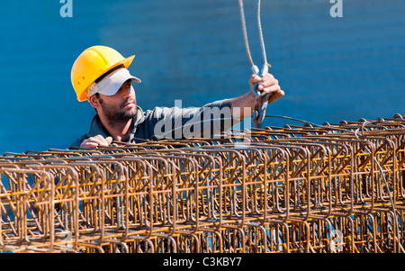 Construction worker loading stack of reinforcement beam cages to crane Stock Photo