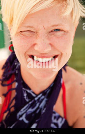 Blonde woman squinting and smiling at camera Stock Photo