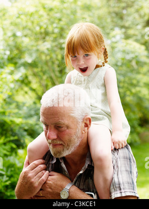 Grandfather carrying granddaughter on shoulder Stock Photo