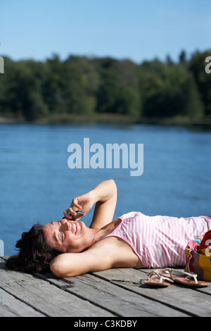A woman on a jetty by a lake, Sweden. Stock Photo