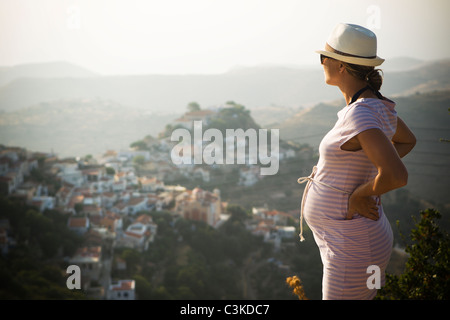 Pregnant woman standing with hand on hip, mountains in background Stock Photo