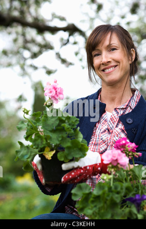 Portrait of a woman setting flowers in a pot. Stock Photo