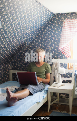 Man using laptop in bed Stock Photo