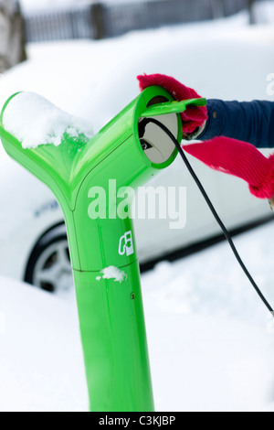 Young woman charging electric car Stock Photo
