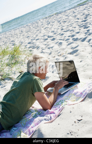 Man using laptop on beach Stock Photo