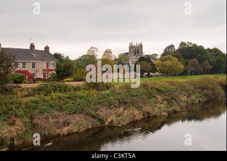 Tall tower of historic C15 Church of St. Mary the Virgin & buildings by  picturesque riverbank - River Wharfe, Tadcaster, North Yorkshire England, UK. Stock Photo