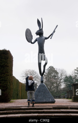 Large Left-Handed Drummer (bronze hare & drum sculpture exhibit by Barry Flanagan) towers over small boy - YSP, Wakefield, Yorkshire, England, UK. Stock Photo