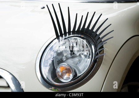 Eye lash / lashes / eyelash / eyelashes attached to a Mini car / car's headlamp / head lamp / headlight / light / lights. Stock Photo