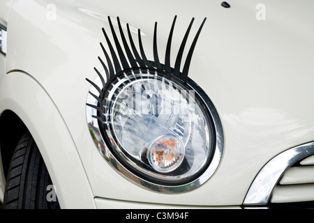 Eye lash / lashes / eyelash / eyelashes attached to a Mini car / car's headlamp / head lamp / headlight / light / lights. Stock Photo