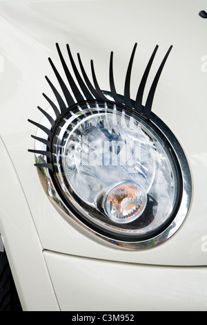 Eye lash / lashes / eyelash / eyelashes attached to a Mini car / car's headlamp / head lamp / headlight / light / lights. Stock Photo