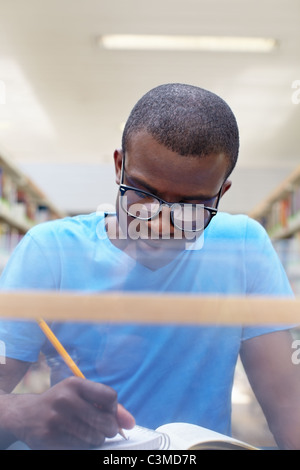 young african american college student reading book in library Stock Photo
