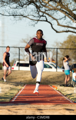 Male African-American high school age athlete runs during a long-jump competition at track meet Stock Photo
