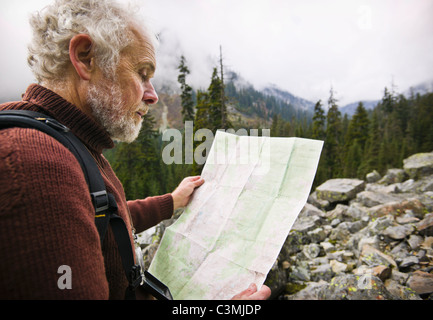 A mature man out in the wilderness using a map to find his way. Washington Cascades, USA. Stock Photo