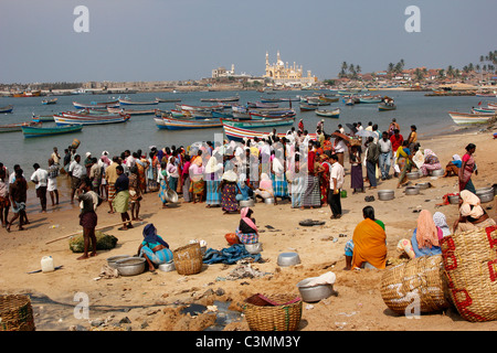 Indian women gather round the fishing boat bringing in its catch in Vizhinjam harbour near Kovalam, Kerala, India Stock Photo