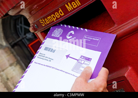 Close up of man person posting completed 2011 census survey form forms postbox England UK United Kingdom GB Great Britain Stock Photo