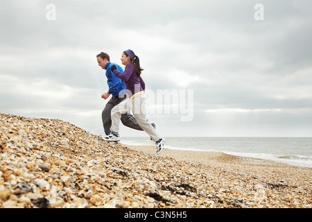 Couple exercising on stoney beach Stock Photo