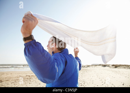 Sporty man celebrating at beach in sun Stock Photo