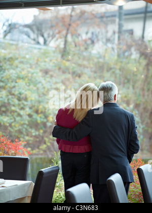 Senior Couple having an intimate moment in a restaurant whilst looking out a window Stock Photo