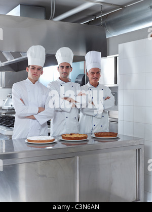 Three generations of chefs in restaurant kitchen with home made cake Stock Photo