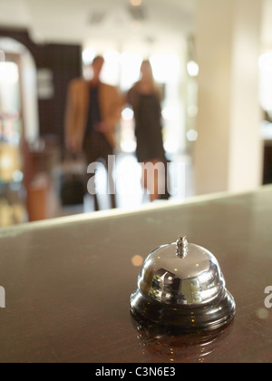 Close up of hotel porters bell with couple approaching Stock Photo