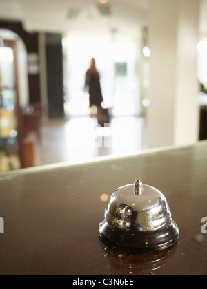 Close up of hotel porters bell with woman approaching Stock Photo
