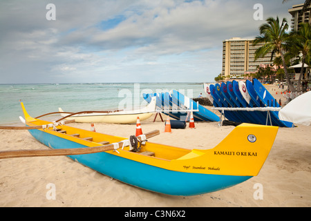 Outrigger canoe and stacked surfboards ready for tourist use in early morning-Waikiki Beach, Honolulu, Oahu, Hawaii, USA.