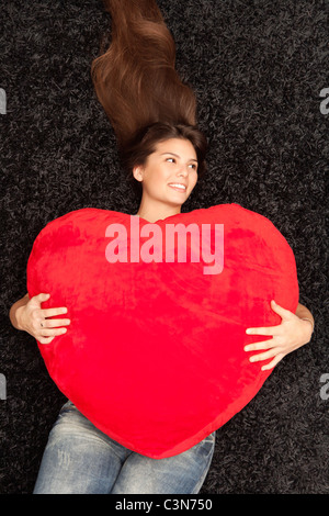 Woman lying with a big heart in her arms Stock Photo