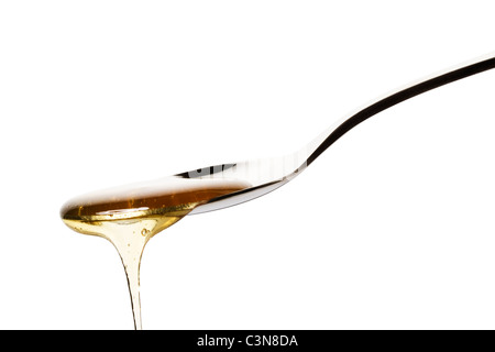 honey falls from a spoon on white background Stock Photo
