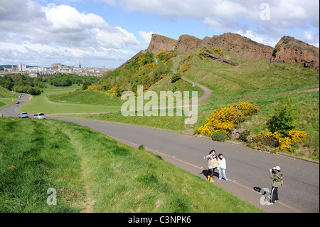 Tourists take a picture next to Salisbury Crags in Holyrood Park in the centre of Edinburgh, Scotland. Stock Photo
