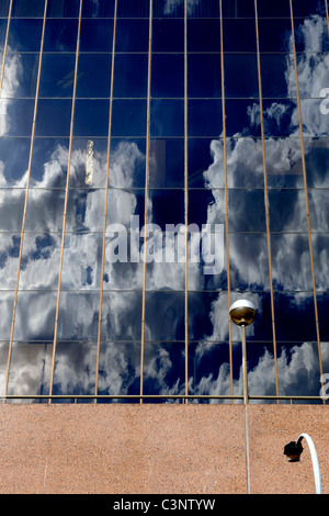 Clouds and sky reflected in windows on modern office building. Metallic ...