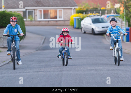 Three boys riding their bikes in a uk street Stock Photo