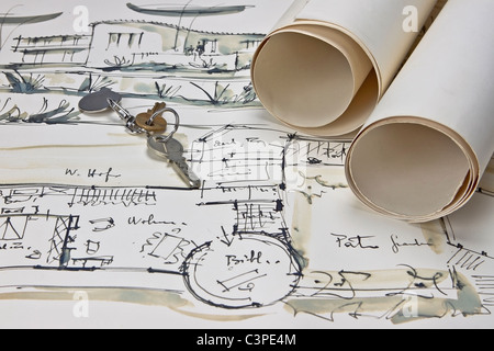 the blueprint of a house with two paper rolls and the keys for the new house Stock Photo