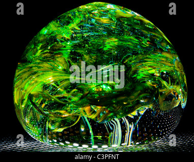 Unusual close up shot of blown glass ball (home made) in the form of a green forest or wood with overhanging leaves Stock Photo