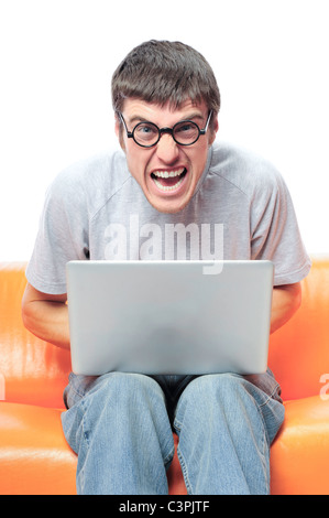 Closeup portrait of funny handsome young relaxing man using laptop and sitting on the sofa, wearing round glasses. Stock Photo