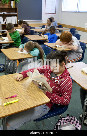 classroom with group of multi-ethnic middle school students sitting, reading and writing at desks Stock Photo