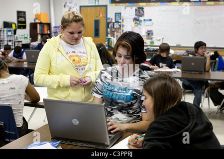 Anglo and Hispanic girls do research together on laptop computer for presentation in social studies class at middle school in TX Stock Photo
