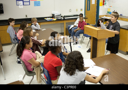 Anglo boy speaks in front of students during mock trial in middle school social studies class in Pflugerville Texas Stock Photo