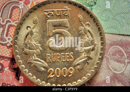Close up of Indian currency coin of denomination Rs.5 of golden color placed on Indian bank notes Stock Photo