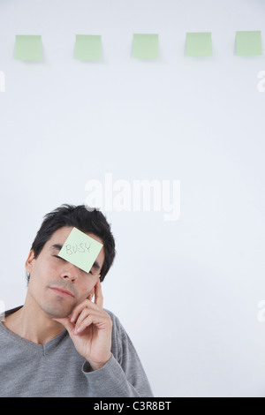 Man with 'busy' post-it note on his head Stock Photo