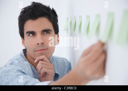 Man arranging post-it notes and thinking Stock Photo