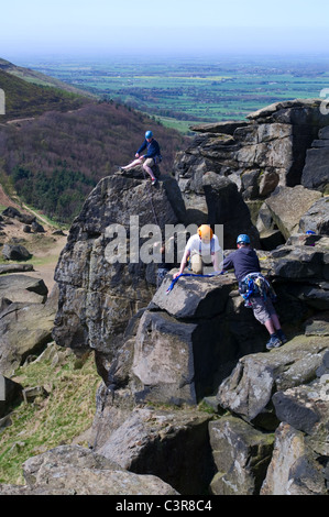4 rock climbers on the Wainstones, Hasty Bank, the Cleveland Way, overlooking Broughton Plantation and Stokesley Plain, N Yorks Stock Photo